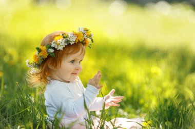 Şirin küçük kız açık havada güzel bir bahar çelengi giyiyor, mesaj için yer var. Kızıl saçlı bebek doğada vakit geçiriyor. 