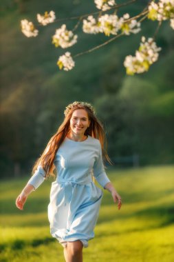  Baharda yeşil tepelerde ilerleyen mavi elbiseli, uzun saçlı güzel mutlu kadının portresi.. 