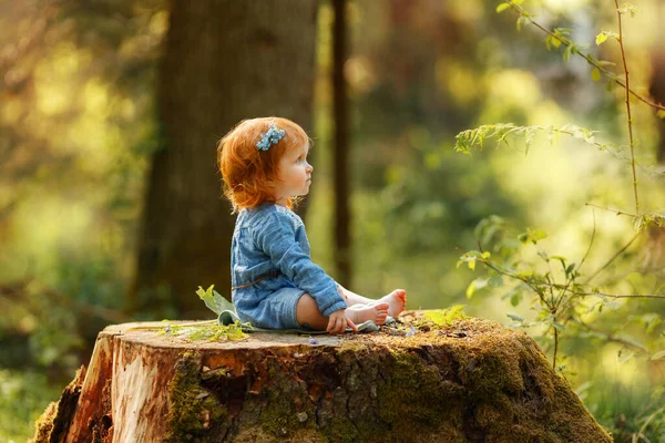 Dziewczynka Niebieskiej Sukience Siedząca Wielkim Pniu Drzewa Parku Patrząca Coś — Zdjęcie stockowe