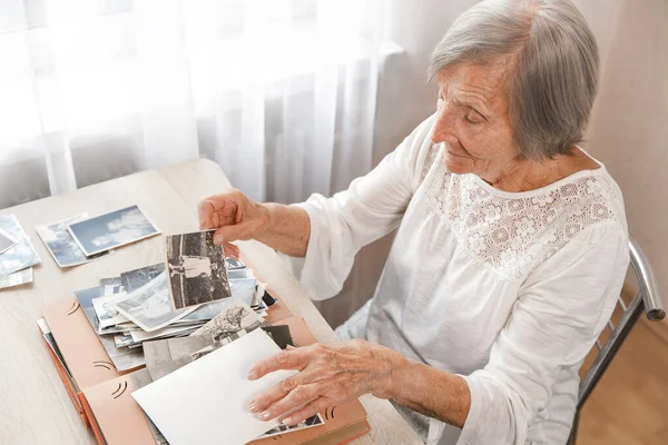 老太太正在家里看她自己的旧照片 老妇人想起自己是多么的年轻和幸福 不禁笑了 有选择的重点 照片拍摄于1953年 — 图库照片