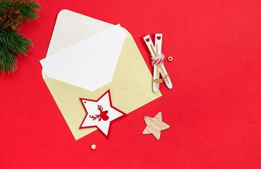 Kırmızı arka planda Noel süsleri olan bir zarf. Yukarıdan görüntüle