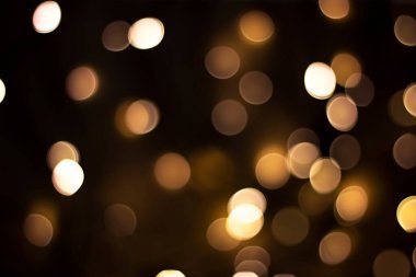 Bokeh. Koyu kahverengi arka planda altın rengi ışıkların çözünmüş hali. Tasarım konsepti