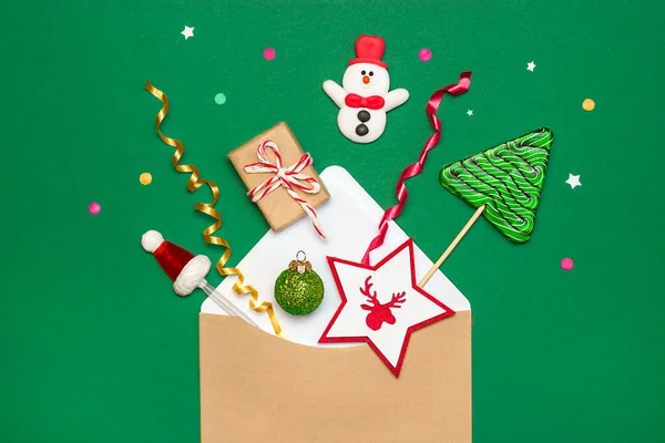 Yeşil arkaplanda noel süsleri olan zarf.