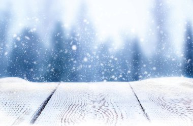 white wooden table in snow on blurred forest background in snowfall
