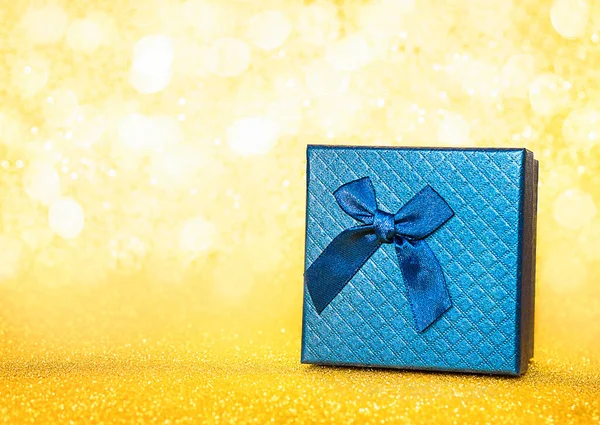 blue gift box with a bow on a yellow shiny background