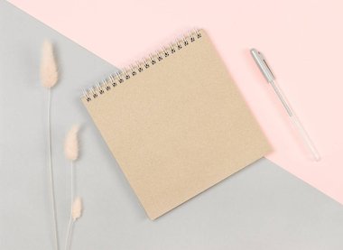 Gri-pembe arka planda kahverengi defter ve kalem. Yukarıdan görüntüle