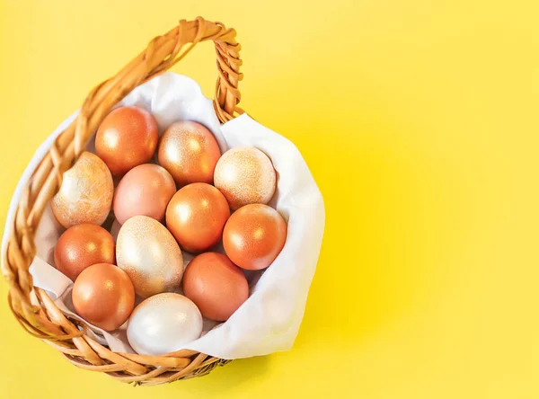 Sarı arka planda renkli yumurtalı bir sepet duruyor. Yukarıdan görüntüle