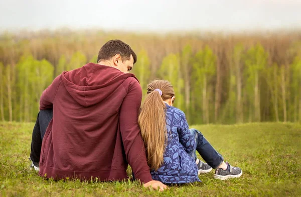Baba ve kızı sırtları ormanda sokakta oturuyorlar. Aile ilişkileri kavramı.