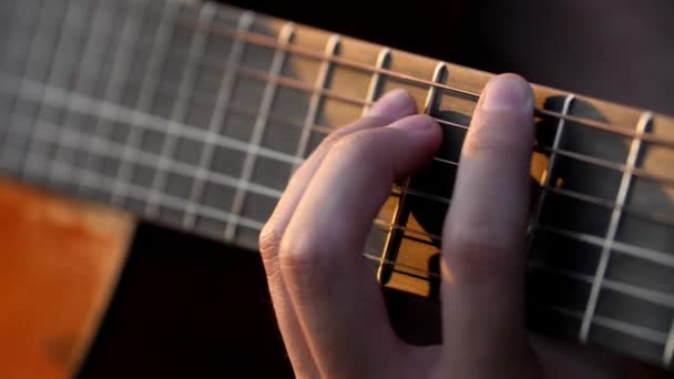 Zbliżenie muzyków palce struganie na struny gitary akustycznej w zachodzie słońca — Wideo stockowe