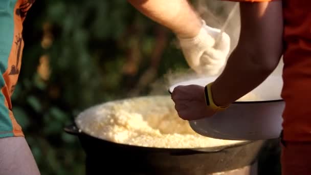Cook places the steaming rice on a steel plate. Camping or field kitchen. — Stock Video