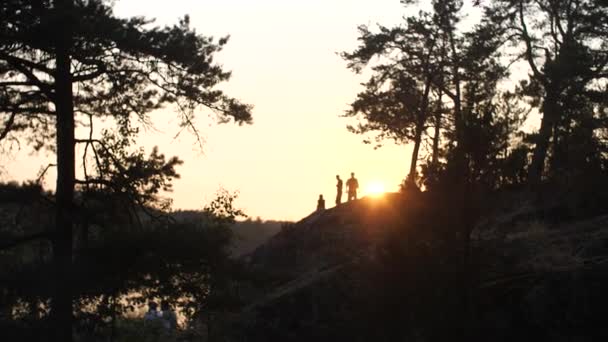 人々は川床の上の崖の上を歩く。夕方の設定オレンジの太陽. — ストック動画