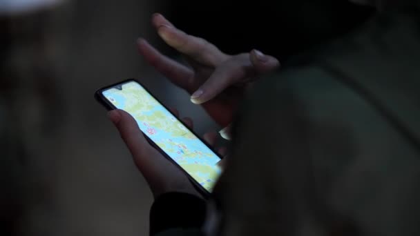 L'uomo tiene in mano un telefono con un'applicazione aperta di una mappa della zona. — Video Stock