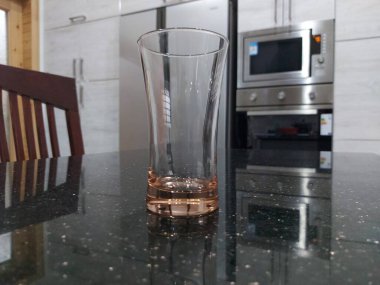 Mutfak aksesuarlı pembe camlı güzel, pırıl pırıl siyah bir masa ve mutfak arka planı..