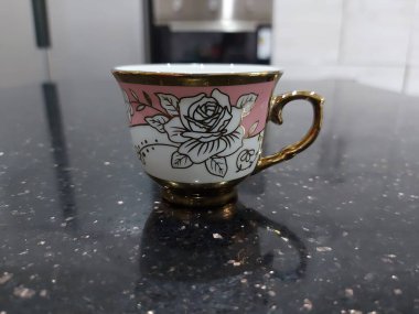 Sevimli, küçük, çiçekli bir mutfak aksesuarı. Parlak, siyah bir masanın üzerinde.