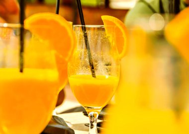 Bir bardak sıkılmış portakallı ve portakallı kokteyl..