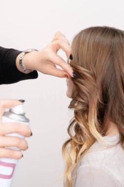 Bir saç stili ustası genç bir kız için modellik yapar. Gerçek hayatta makyaj ve kozmetoloji konsepti. Parlak makyajlı güzel genç bir model.