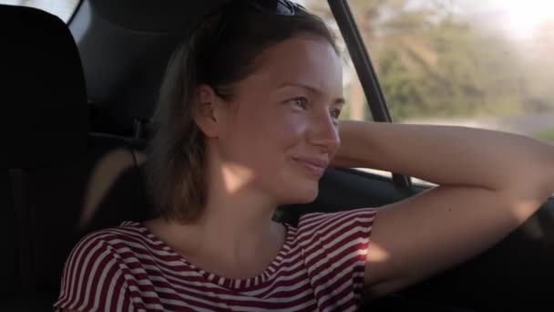 Jeune femme assise sur le siège arrière d'un taxi regardant vers la fenêtre et souriant — Video
