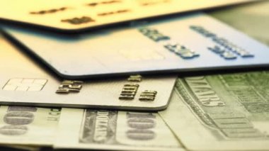 Bir dolarlık banknotlar ve alışveriş masasında dönen plastik kredi kartları.