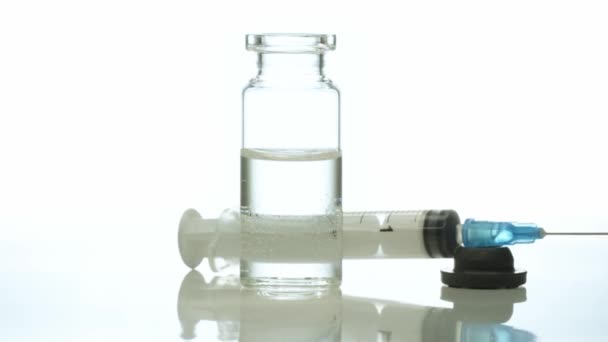 Медицинская стеклянная бутылка с медицинским шприцем вращается на белом фоне — стоковое видео