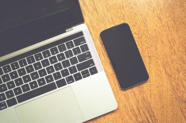 Modern dizüstü bilgisayar ve akıllı telefon ahşap masanın üstünde.