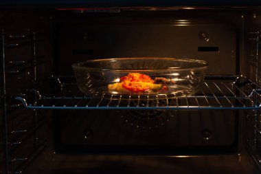 Ev fırınında marine edilmiş et pişirme süreci. Kızarmış et için domatesli, peynirli ve baharatlı birkaç parça et..