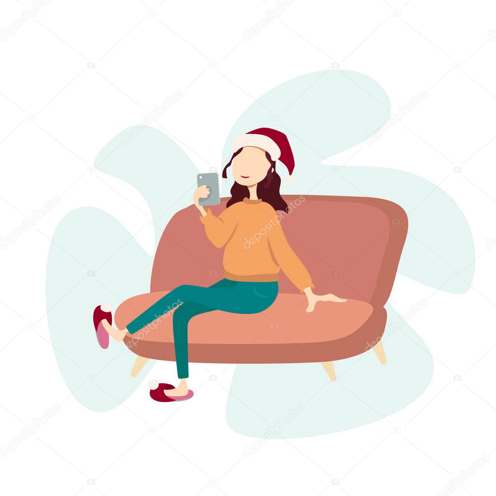 A girl with a mobile phone in her hand sits on the sofa in a christmas hat.