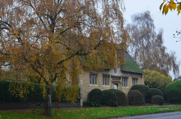 Stary angielski dom jesienią, obok brzozy z żółtymi liśćmi. — Zdjęcie stockowe