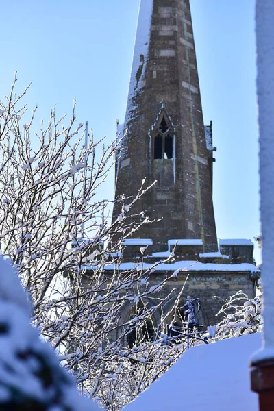 Die Turmspitze der alten viktorianischen Kirche liegt im Schnee, vor blauem Himmel. — Stockfoto