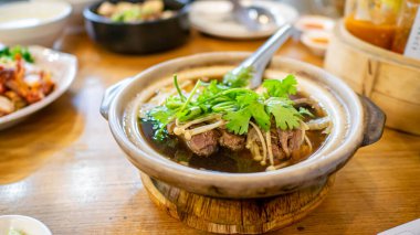 Bak Kut Teh, Tayland, Bangkok 'taki Tayland restoranındaki ahşap masada geleneksel kase içinde Çin domuz pirzolası çorbası..