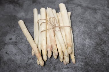 Taş bir masanın üzerinde bir sürü taze kuşkonmaz