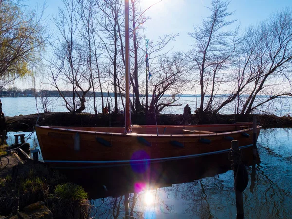 Деревянная парусная лодка пришвартована на берегу на закате — стоковое фото