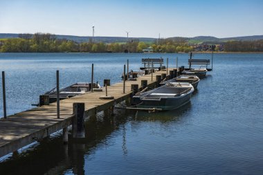 Mavi gölde sandalları olan ahşap iskele.