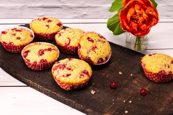 Several currants muffins served on an old wooden board with bouquet of flowers — Stock Photo, Image