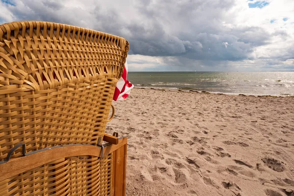 Sandy beach by the sea with german beach chair and dramatic thunderclouds — Fotografia de Stock