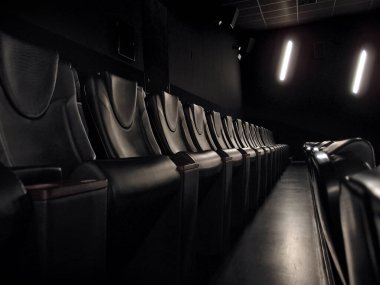 Sinema salonunun karanlığında boş siyah deri koltuklar