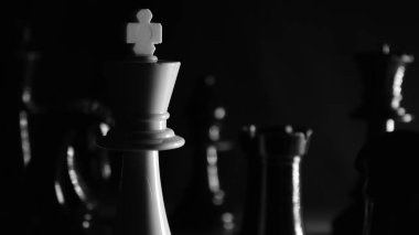 Beyaz satranç kraliçesi siyah ve beyaz kapak siyah parçalarla çevrili, gölgeli