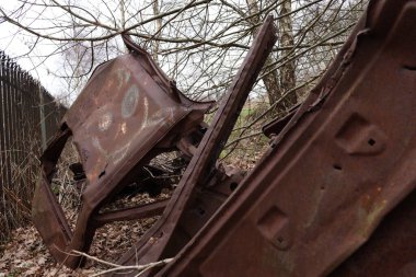 Terk edilmiş, kırılmış, paslanmış, gülen yüzlü bir araba.