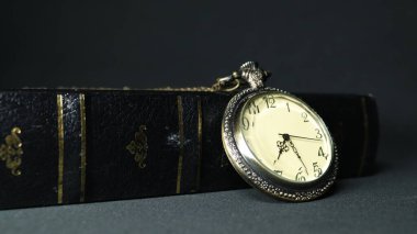 Eski cep saati siyah deri kitaba karşı dinleniyor.