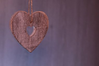 Tahta kalp, gri bir arkaplanda iple asılı duruyor.