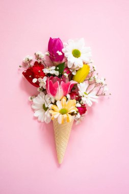 Dondurma külahında bahar çiçekleri pembe arka planda