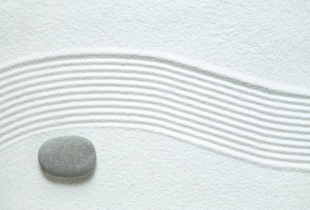 Zen garden with a single stone on white sand 