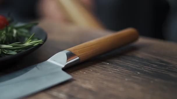 Mano toma cuchillo de cocina de la mesa de madera — Vídeo de stock