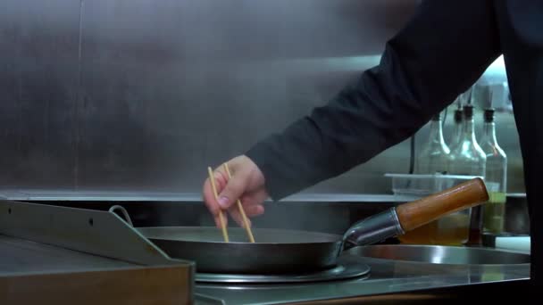 Chef mescolando tagliatelle bollenti con bastoncini di costoletta in una padella. — Video Stock