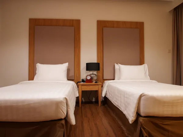Double bed in the modern interior room with two white pillows and white bath towels
