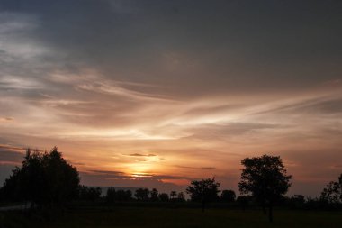 Muhteşem günbatımı sona erdi, ufukta turuncu güneş yükseliyor.