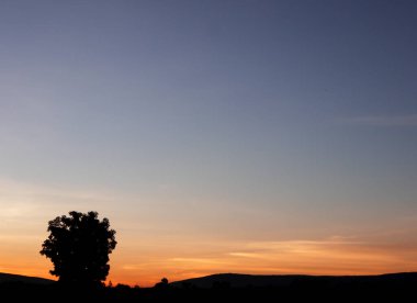 Muhteşem günbatımı sona erdi, ufukta turuncu güneş yükseliyor.