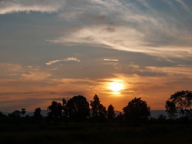 Muhteşem günbatımı sona erdi, ufukta turuncu güneş yükseliyor.