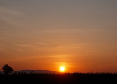 Muhteşem günbatımı sona erdi, ufukta turuncu güneş yükseliyor.