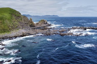 Deniz dalgaları kayalık kıyılara çarpıyor.