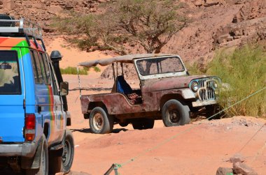 Taşların arkasındaki kumların arasında bir araba.